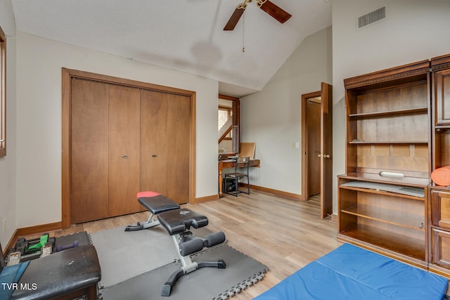 workout area featuring lofted ceiling, a textured ceiling, ceiling fan, light wood-type flooring, and built in desk