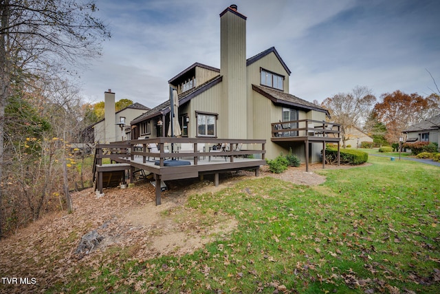 rear view of house featuring a wooden deck and a lawn