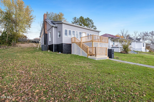 view of front of home featuring a deck, a front yard, and central AC