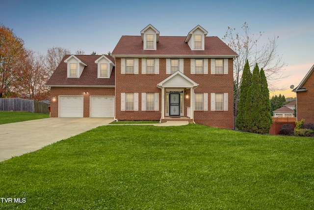 colonial home with a garage and a yard