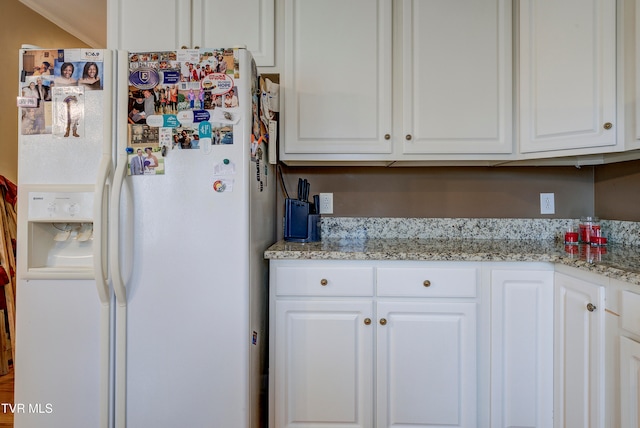 kitchen with white cabinetry, white fridge with ice dispenser, crown molding, and light stone countertops