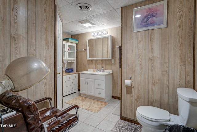 bathroom featuring toilet, tile patterned flooring, a paneled ceiling, wood walls, and vanity