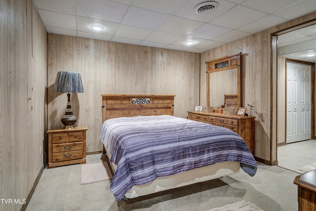 carpeted bedroom featuring a paneled ceiling and wooden walls