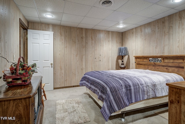 carpeted bedroom with a paneled ceiling and wooden walls