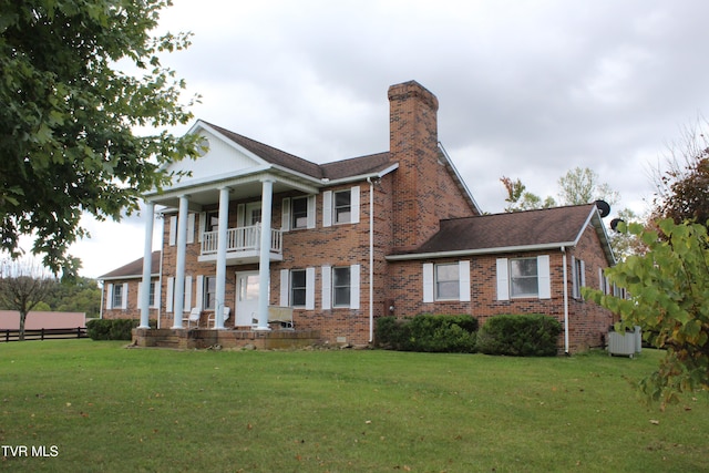 view of front of home with a balcony and a front yard