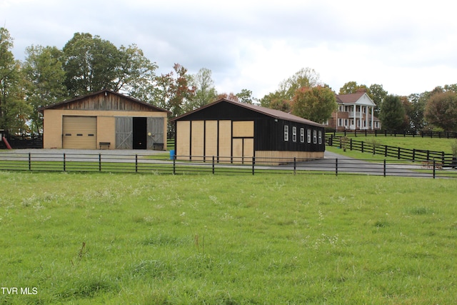 view of yard featuring an outbuilding, a garage, and a rural view