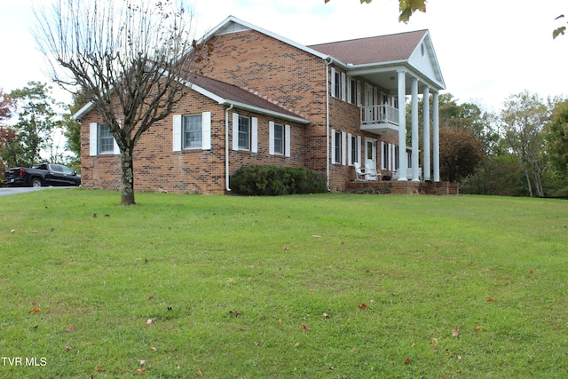 view of side of property with a yard and a balcony