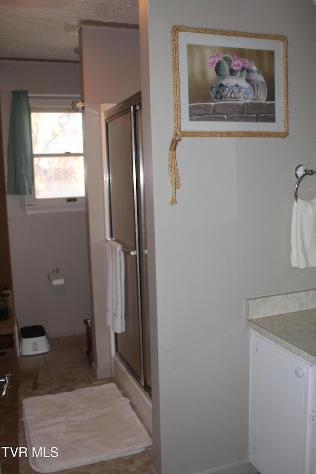 bathroom featuring vanity, a textured ceiling, and a shower with door