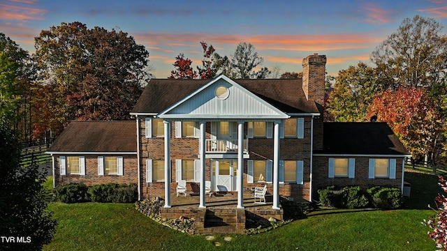 view of front of property with a lawn and a balcony