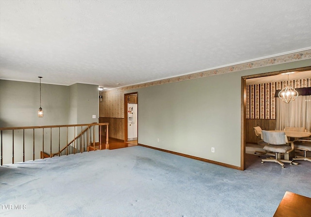 empty room with carpet flooring, a textured ceiling, and a notable chandelier