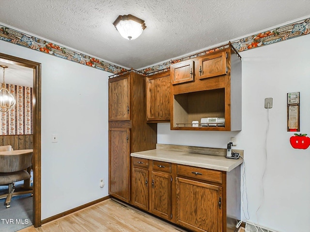 kitchen featuring decorative light fixtures, an inviting chandelier, a textured ceiling, and light hardwood / wood-style flooring