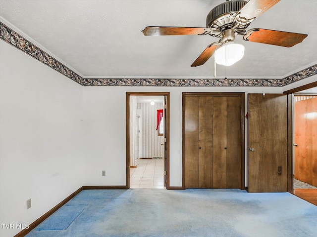 unfurnished bedroom featuring ceiling fan, light colored carpet, a textured ceiling, and ornamental molding