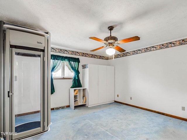 spare room featuring ceiling fan, light colored carpet, and a textured ceiling