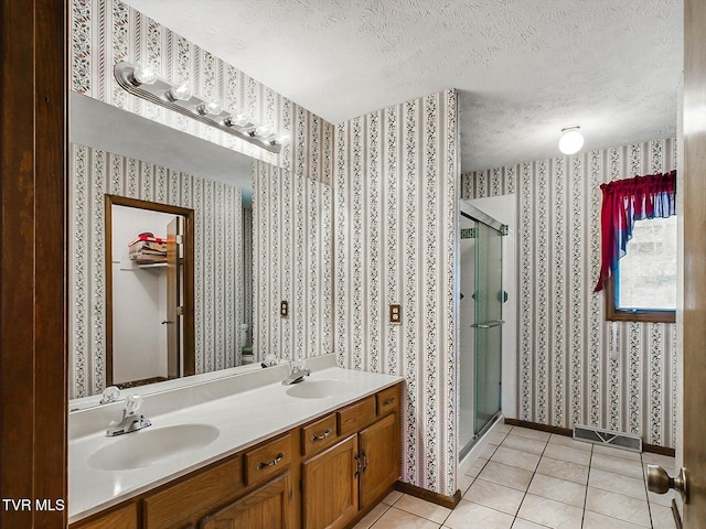 bathroom with tile patterned flooring, vanity, a textured ceiling, and walk in shower