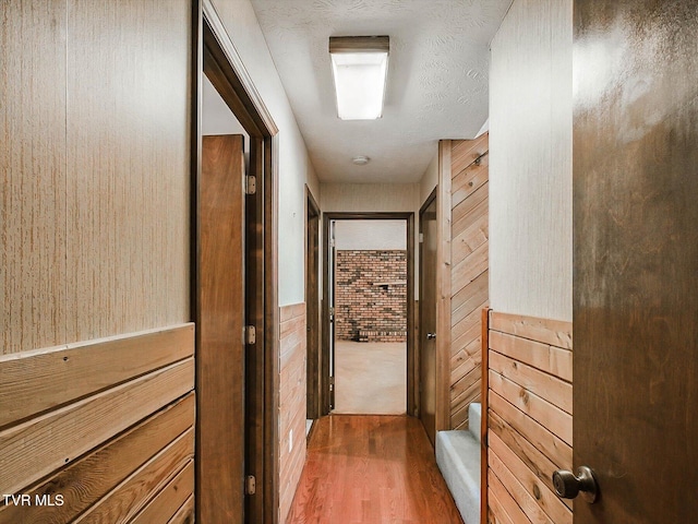 hallway with hardwood / wood-style flooring and wooden walls