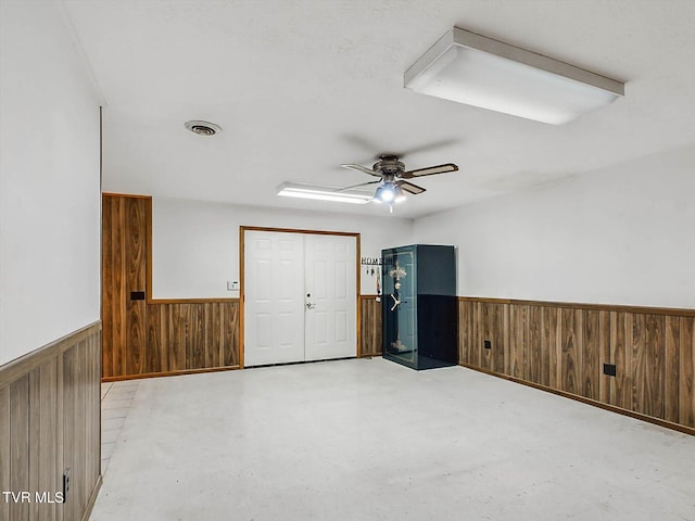 spare room with ceiling fan and wooden walls