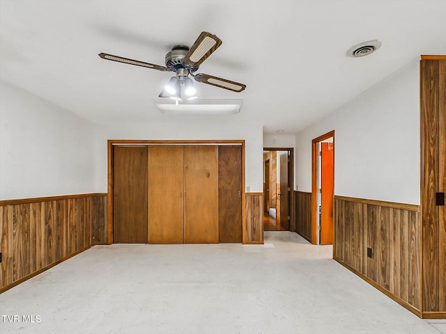 bedroom with ceiling fan, wood walls, and a closet