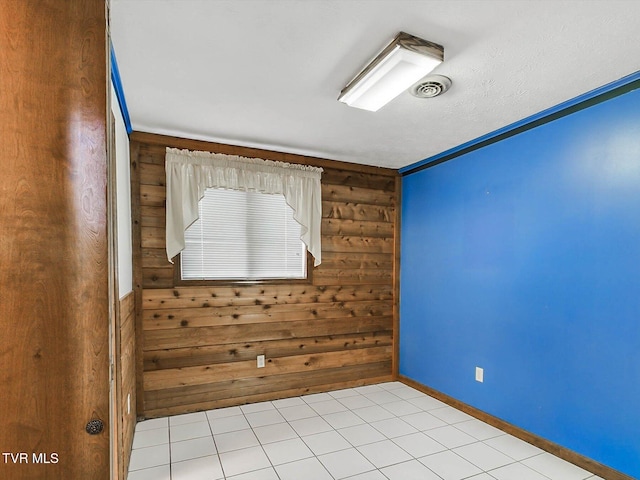 unfurnished room with light tile patterned floors, crown molding, and wooden walls