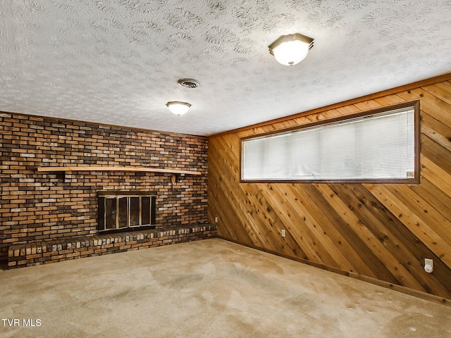 unfurnished living room featuring wooden walls, a fireplace, carpet floors, and a textured ceiling