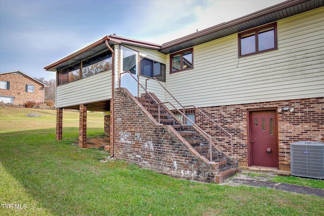 back of house featuring a sunroom, central AC, and a lawn