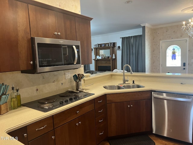 kitchen with ornamental molding, stainless steel appliances, sink, dark wood-type flooring, and a chandelier