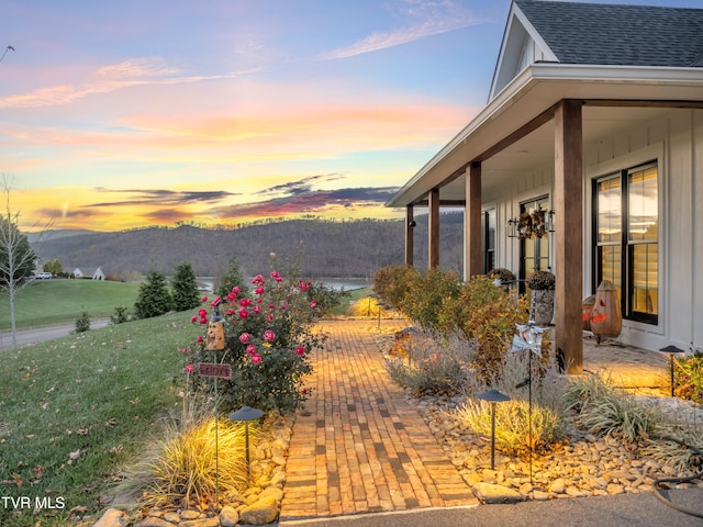 patio terrace at dusk featuring a lawn and a mountain view