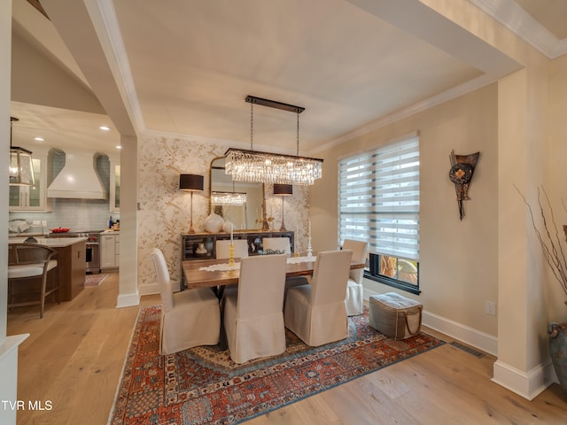 dining area with a chandelier, light hardwood / wood-style flooring, and ornamental molding