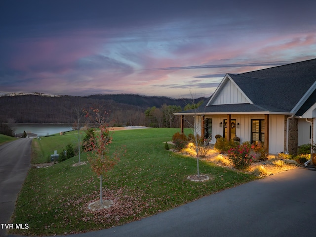 view of front of home with a porch, a water view, and a yard