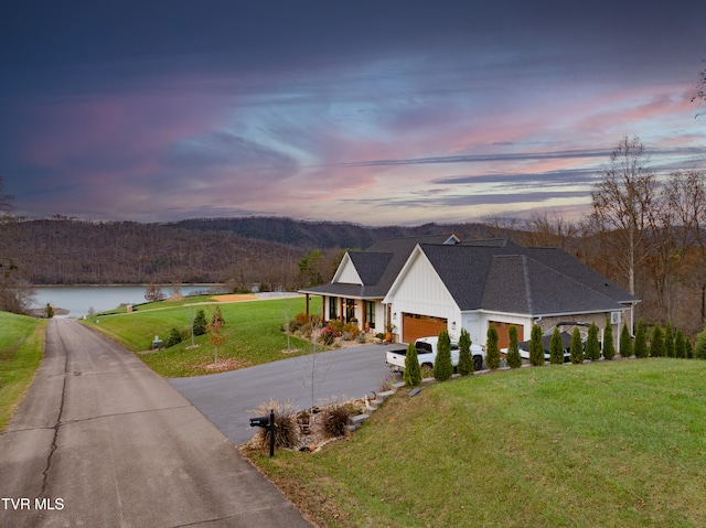 view of front of house with a garage, a water view, and a lawn