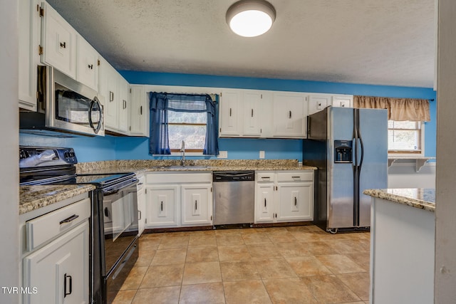 kitchen with light stone countertops, sink, white cabinets, and stainless steel appliances