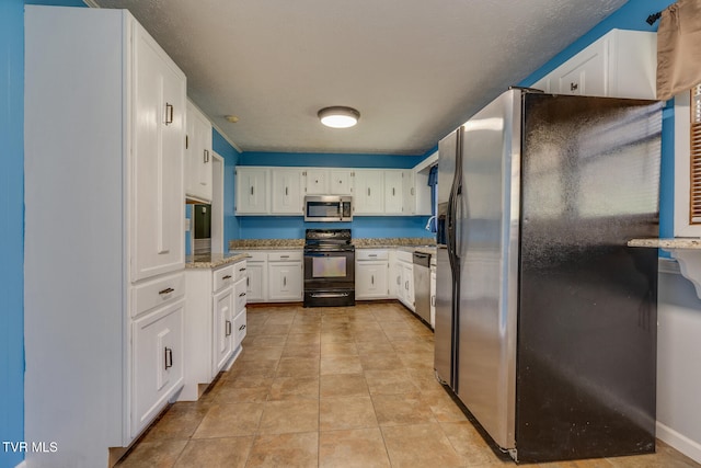 kitchen with appliances with stainless steel finishes, light tile patterned floors, white cabinetry, and light stone counters