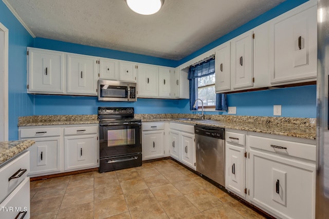 kitchen featuring light stone countertops, sink, a textured ceiling, white cabinets, and appliances with stainless steel finishes