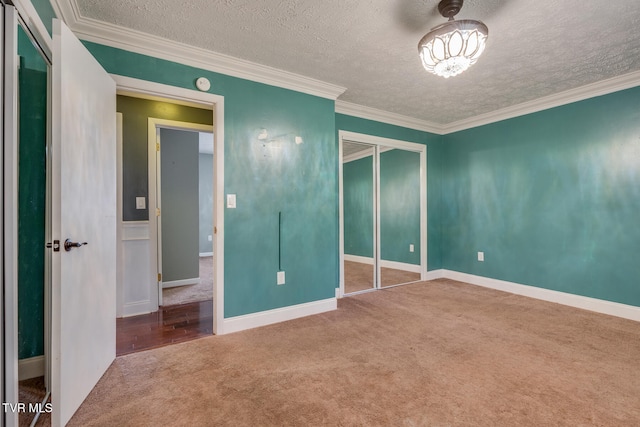 unfurnished bedroom with carpet flooring, a closet, a textured ceiling, and ornamental molding