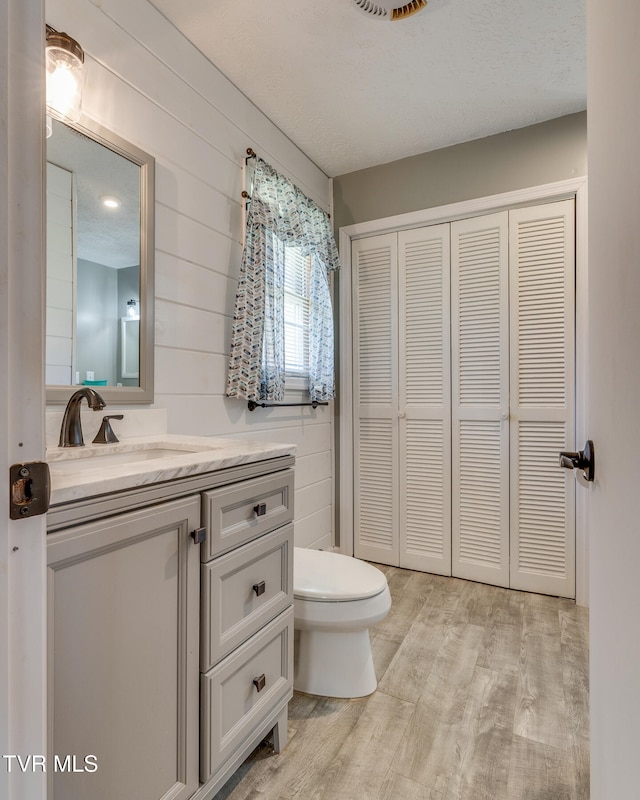 bathroom featuring wood walls, toilet, vanity, and hardwood / wood-style flooring