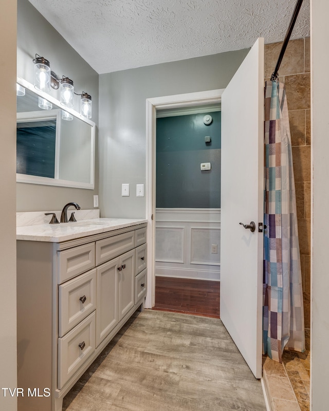 bathroom with a shower with curtain, vanity, a textured ceiling, and hardwood / wood-style flooring