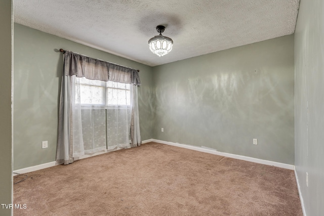 carpeted empty room featuring a textured ceiling