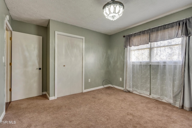 unfurnished bedroom with a textured ceiling and light colored carpet