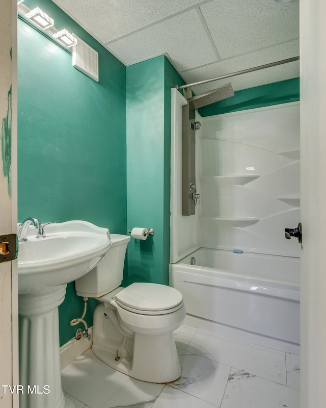 bathroom with a drop ceiling, shower / bathtub combination, and toilet