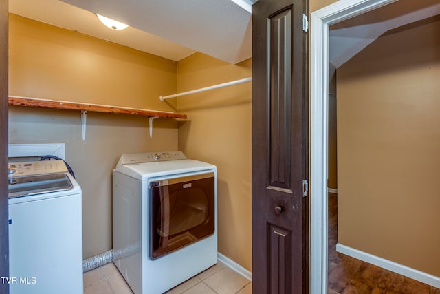 clothes washing area with washer and clothes dryer and light tile patterned floors