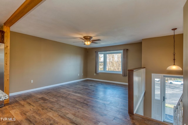 spare room with ceiling fan, dark hardwood / wood-style floors, and beamed ceiling