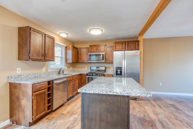 kitchen featuring light wood-type flooring, stainless steel appliances, a center island, and light stone countertops