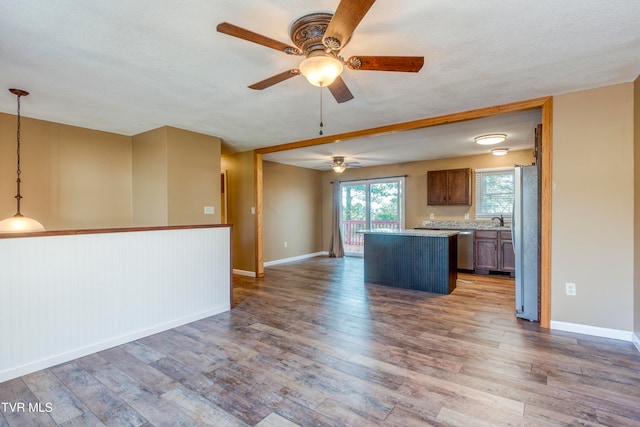 kitchen with stainless steel appliances, hardwood / wood-style flooring, decorative light fixtures, and a kitchen island