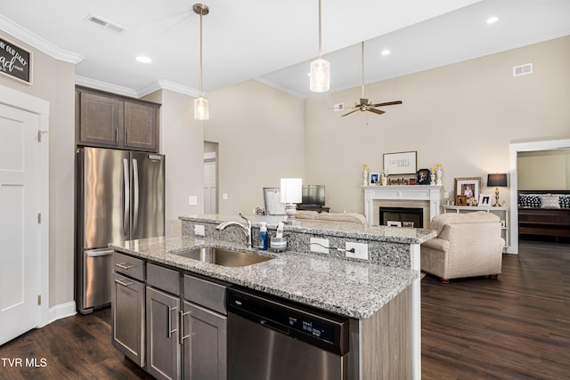 kitchen with sink, light stone counters, appliances with stainless steel finishes, decorative light fixtures, and dark wood-type flooring