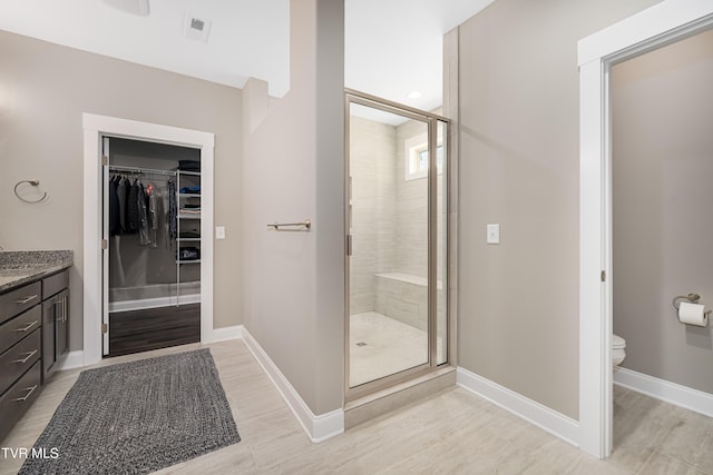 bathroom featuring toilet, vanity, hardwood / wood-style flooring, and a shower with shower door