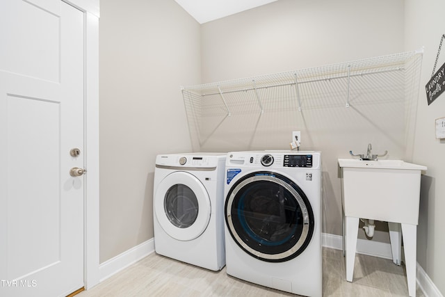 laundry area with independent washer and dryer and light hardwood / wood-style flooring