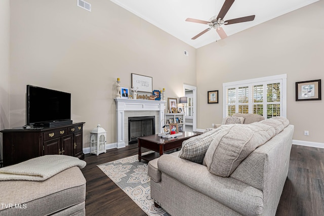 living room with a tiled fireplace, high vaulted ceiling, dark hardwood / wood-style flooring, and ceiling fan