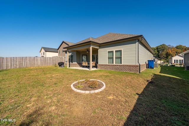 rear view of house featuring ceiling fan, a patio, and a yard