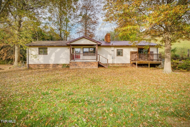 rear view of property featuring metal roof, a lawn, a wooden deck, and a chimney