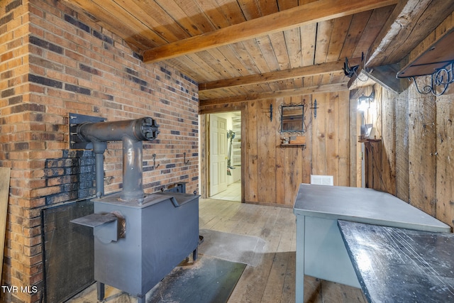 living room with beam ceiling, hardwood / wood-style floors, wood walls, wood ceiling, and a wood stove