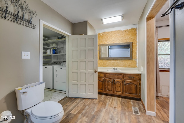 bathroom featuring washing machine and dryer, wood-type flooring, vanity, and toilet